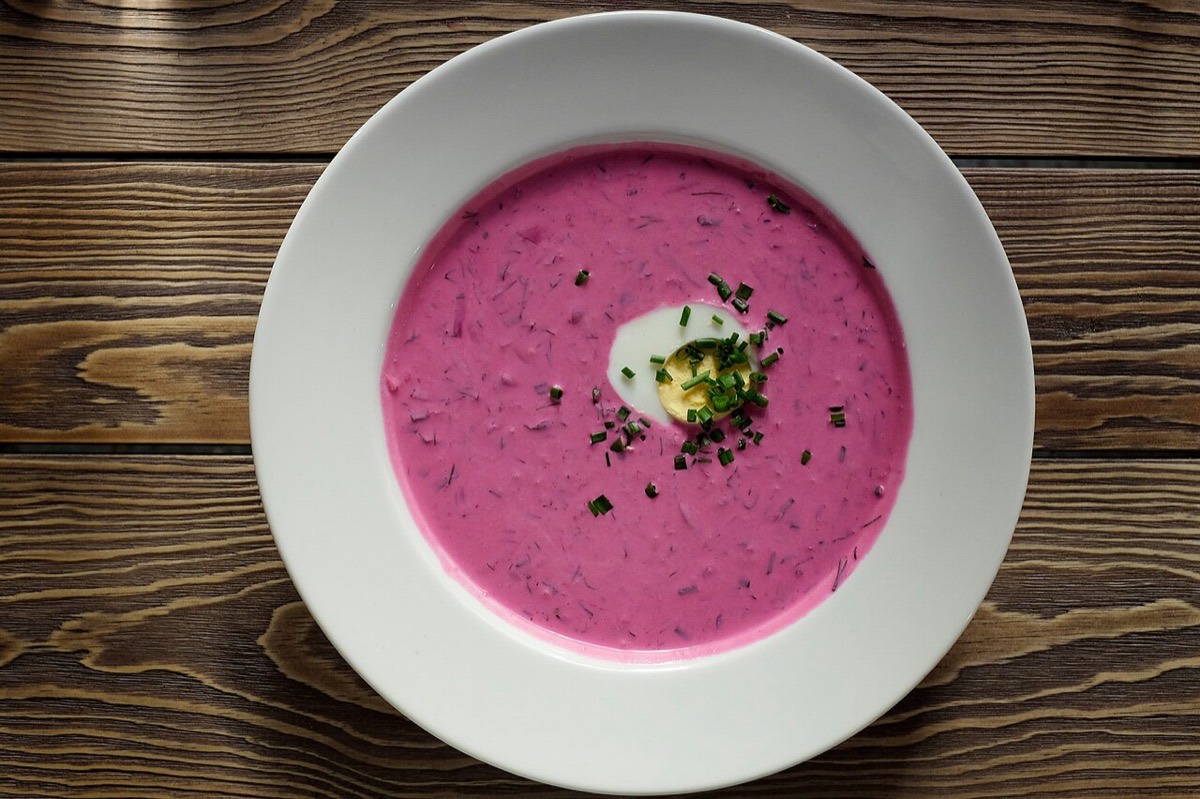 A bowl of vivid pink kholodnik cold beet soup with egg and dill