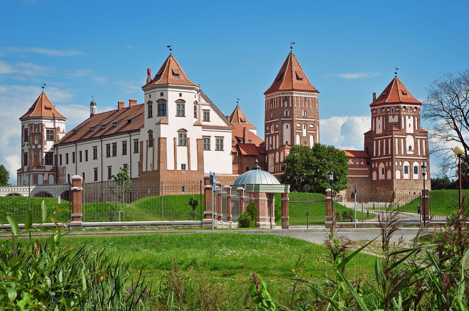 Mir Castle rising above its lake on a summer day